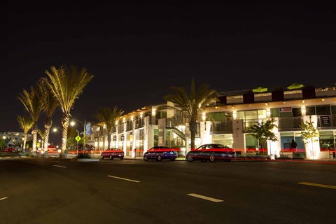 a city street at night with cars parked in front of a building