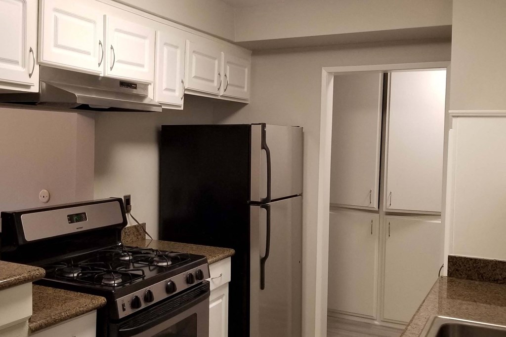 a kitchen with white cabinets and a black refrigerator