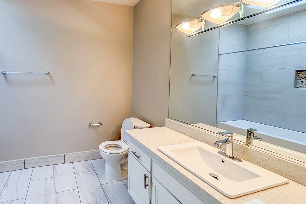 A bathroom with a toilet, sink, and mirror.