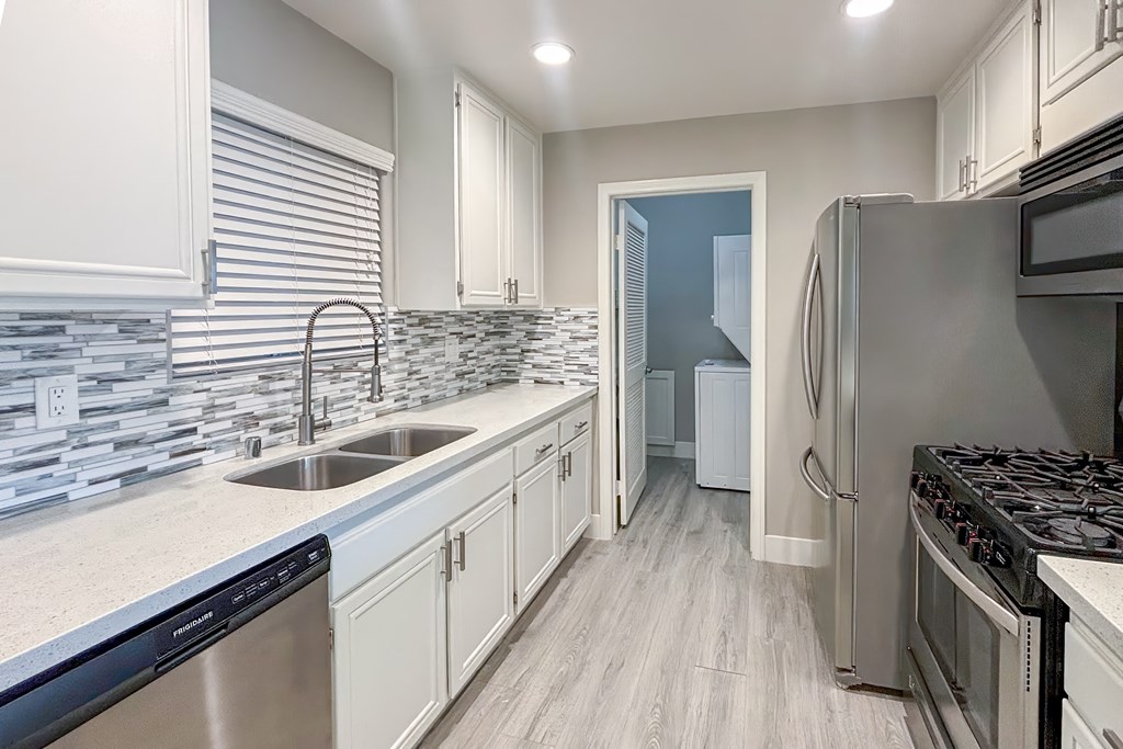 A kitchen with a stainless steel refrigerator, dishwasher, and oven.