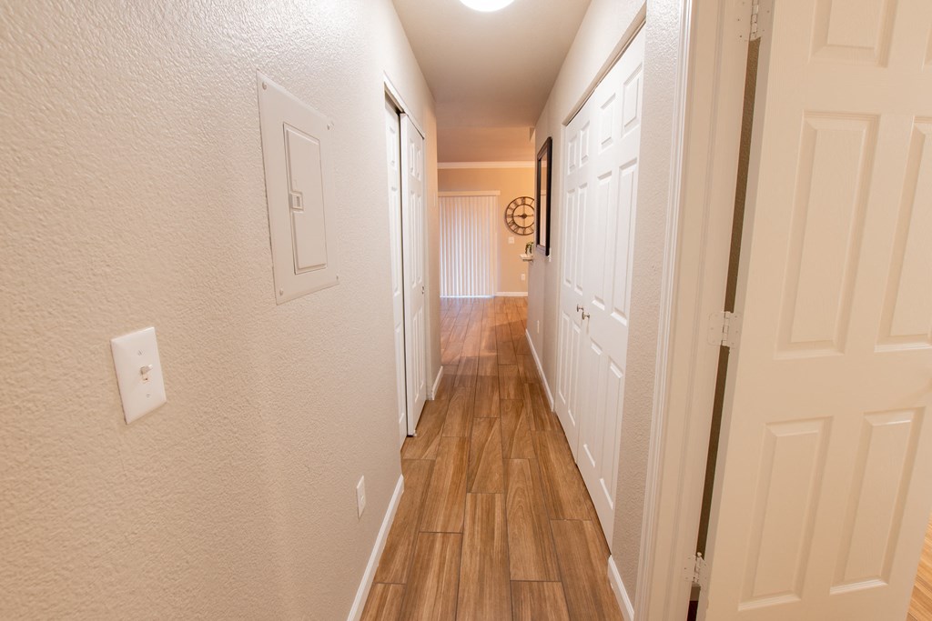 a long hallway with wood floors and white closets and doors