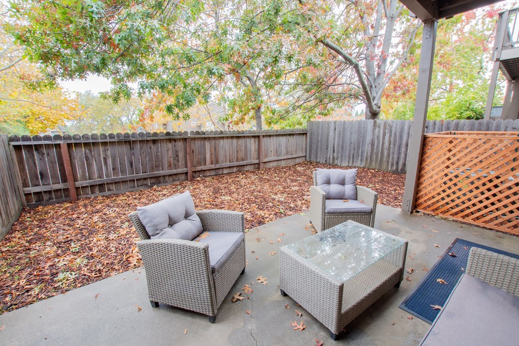 a patio with chairs and a table in front of a fence