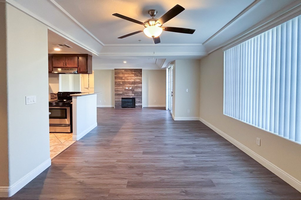 A spacious living room with a ceiling fan and hardwood floors.