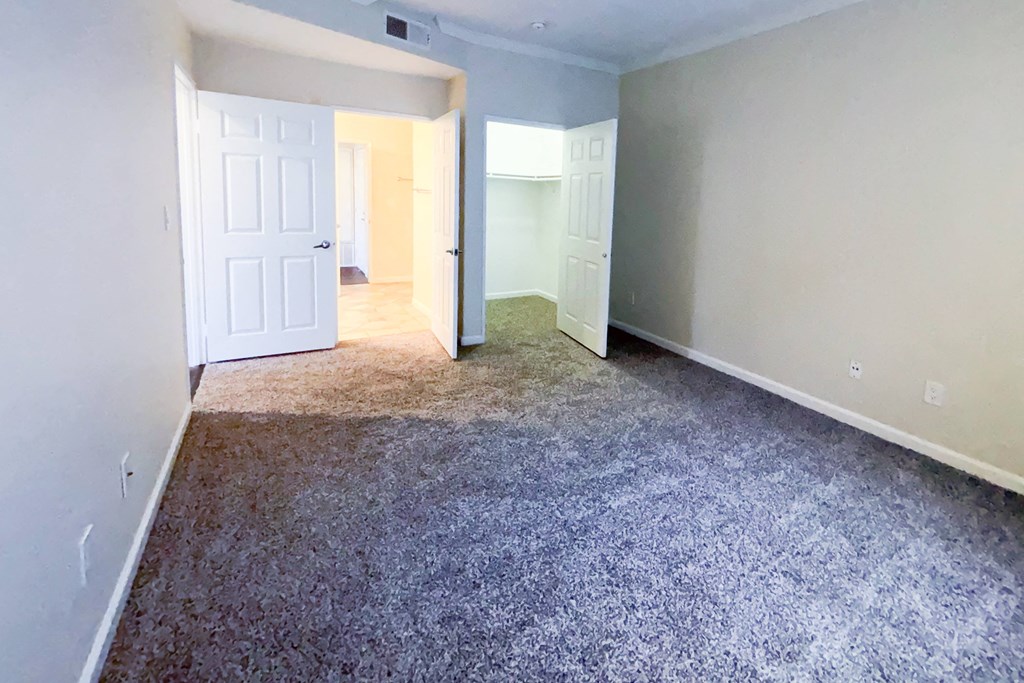 A room with a carpeted floor and two doors.