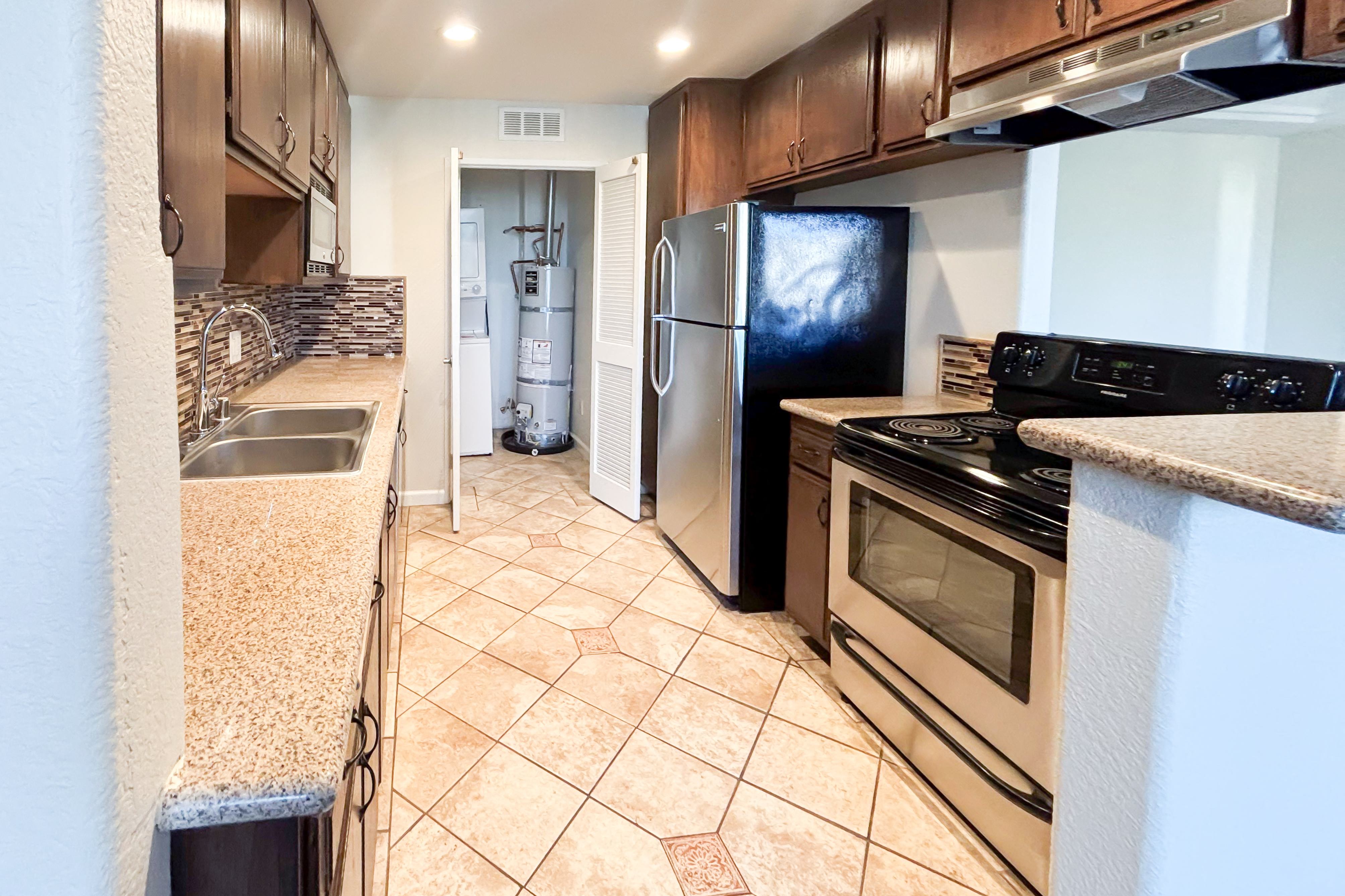 A kitchen with a black fridge and stove top oven.