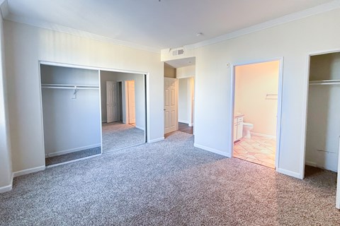 A sparsely furnished apartment with a carpeted floor and white walls.