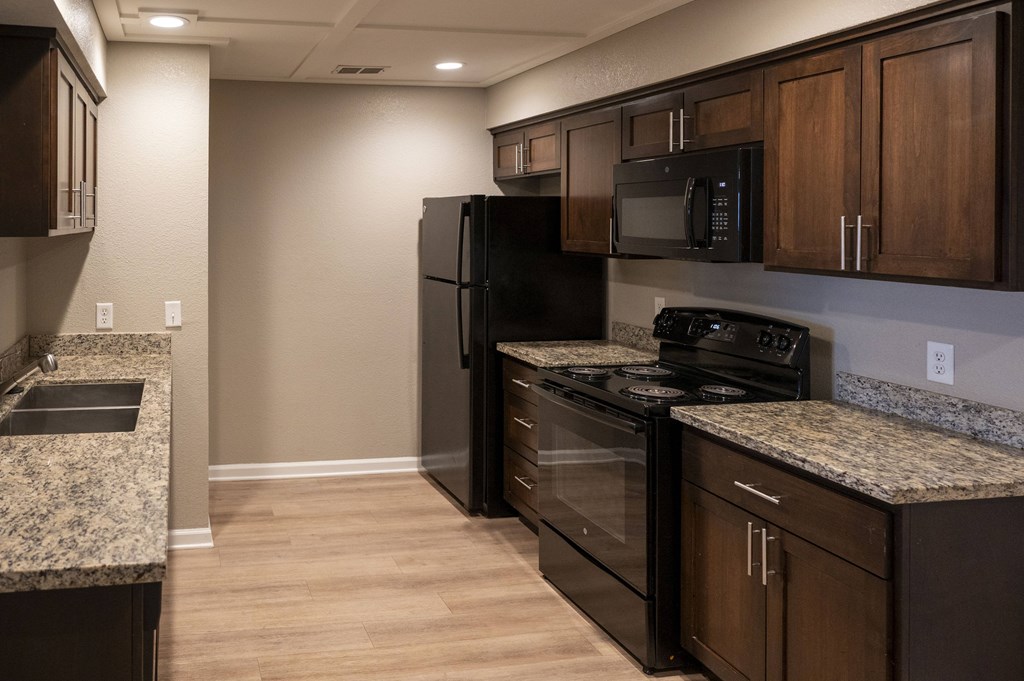 A kitchen with black appliances and wooden cabinets at Sierra Oaks Living Apartments, Cameron Park, California