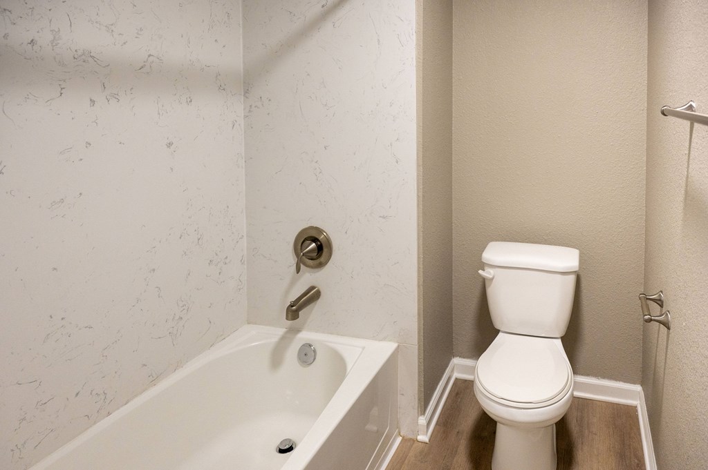 A white toilet sits next to a bathtub in a bathroom at Sierra Oaks Living Apartments, Cameron Park 95682