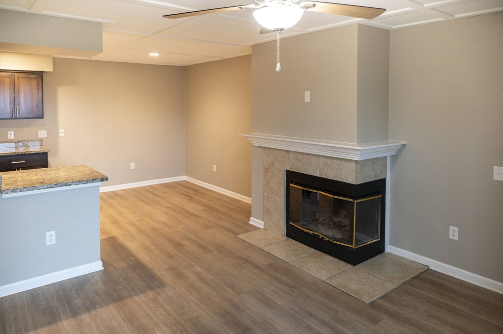 A living room with a fireplace and a ceiling fan at Sierra Oaks Living Apartments, Cameron Park, California