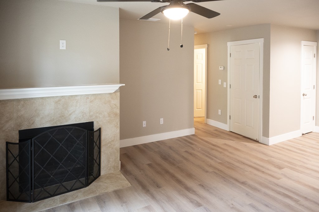 A living room with a fireplace and a ceiling fan at Sierra Oaks Living Apartments, California 95682