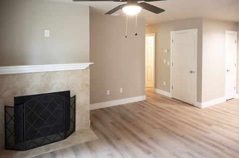 A living room with a fireplace and a ceiling fan.