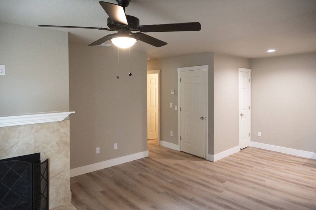 A room with a fireplace and a ceiling fan at Sierra Oaks Living Apartments, California