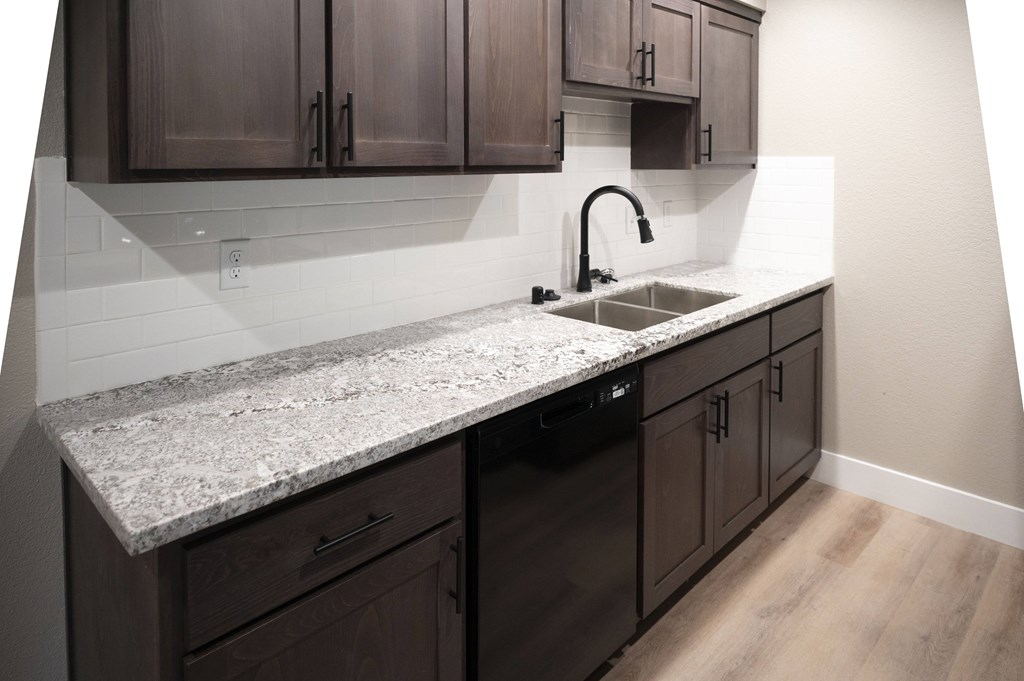 A kitchen with a granite countertop and dark brown cabinets at Sierra Oaks Living Apartments, Cameron Park