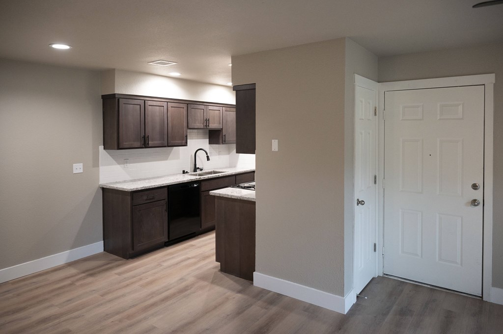 A kitchen with brown cabinets and a white door at Sierra Oaks Living Apartments, Cameron Park, CA 95682