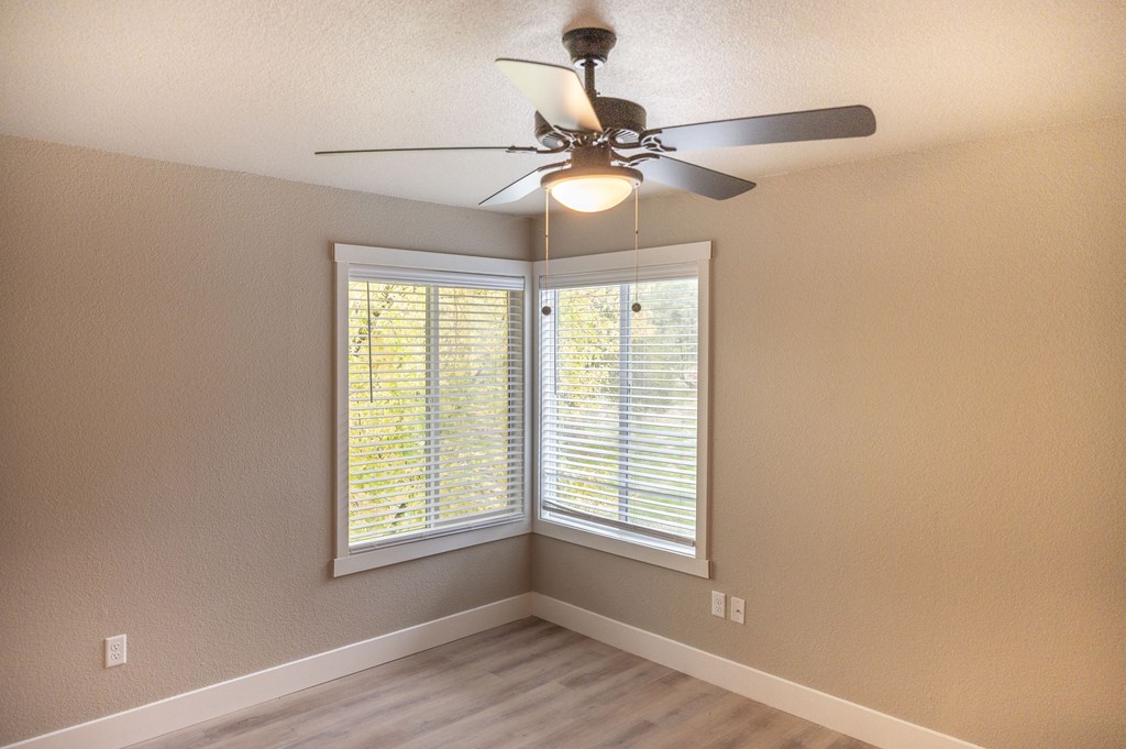 A room with a ceiling fan and a window with blinds at Sierra Oaks Living Apartments, California