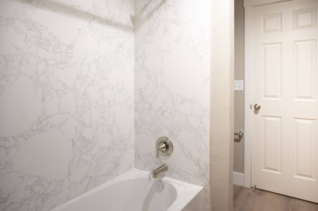 A white bathroom with a marble patterned wall at Sierra Oaks Living Apartments, California 95682
