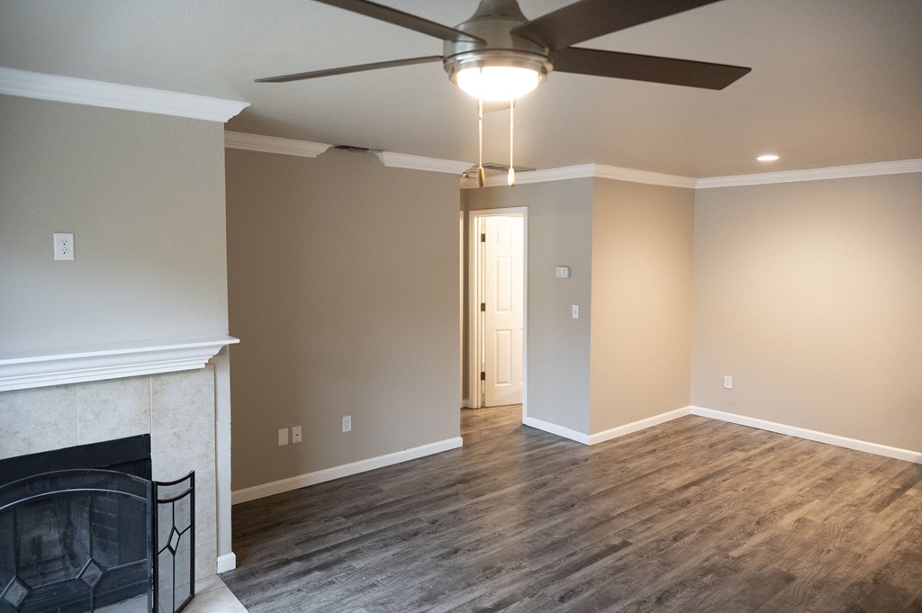 A room with a fireplace and a ceiling fan at Sierra Oaks Living Apartments, California