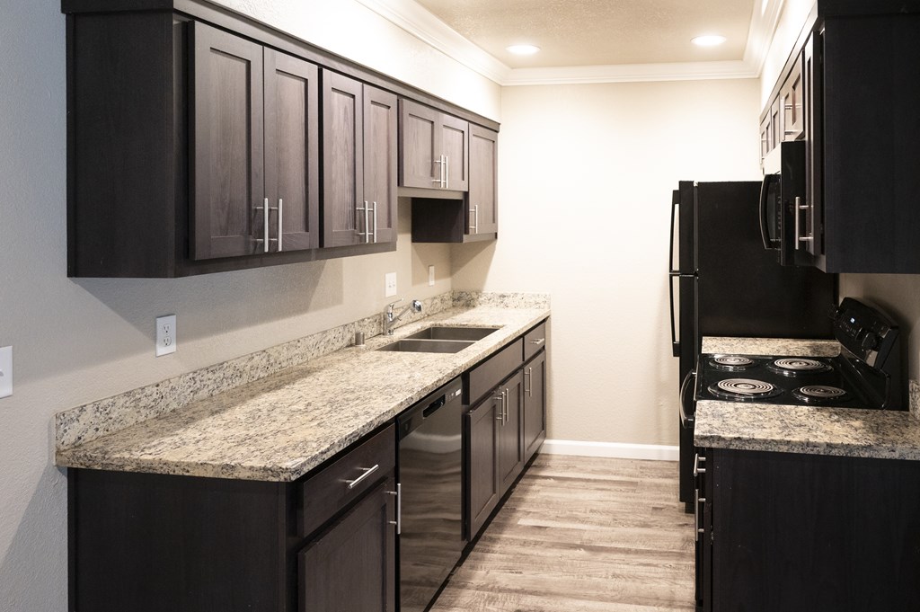 A kitchen with dark brown cabinets and granite countertops at Sierra Oaks Living Apartments, Cameron Park, CA 95682