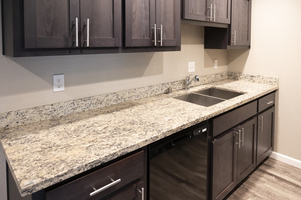 A kitchen with granite countertops and dark brown cabinets at Sierra Oaks Living Apartments, Cameron Park