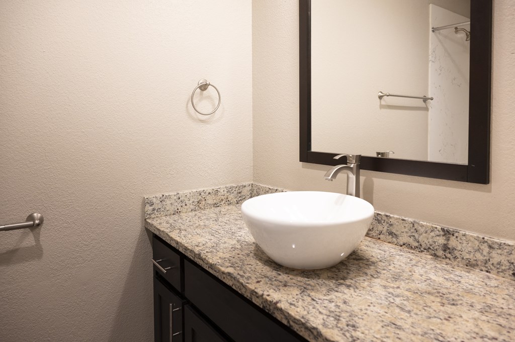 A white sink is on a granite countertop in a bathroom at Sierra Oaks Living Apartments, Cameron Park, California