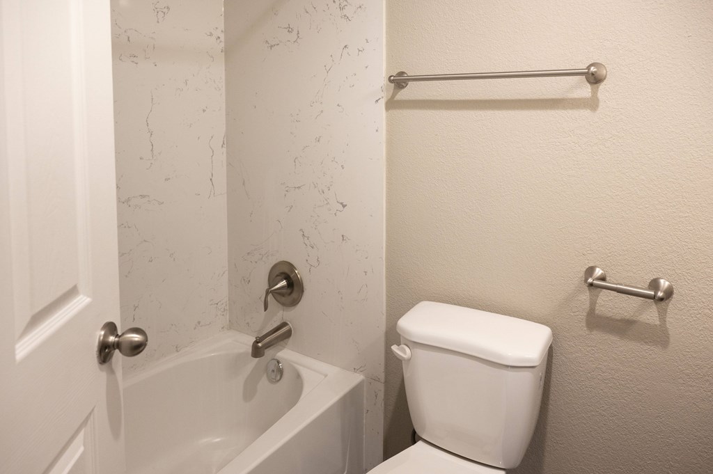 A white toilet sits next to a bathtub in a bathroom at Sierra Oaks Living Apartments, Cameron Park