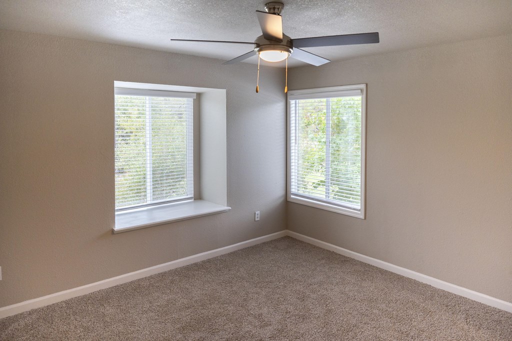 A room with a ceiling fan and two windows at Sierra Oaks Living Apartments, Cameron Park, CA