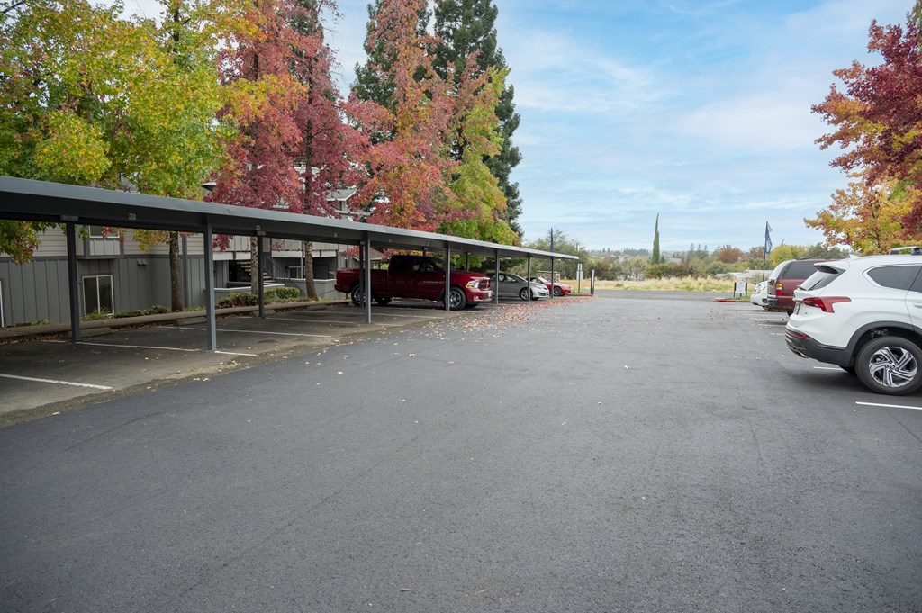 A parking lot with a white car parked in the foreground at Sierra Oaks Living Apartments, Cameron Park