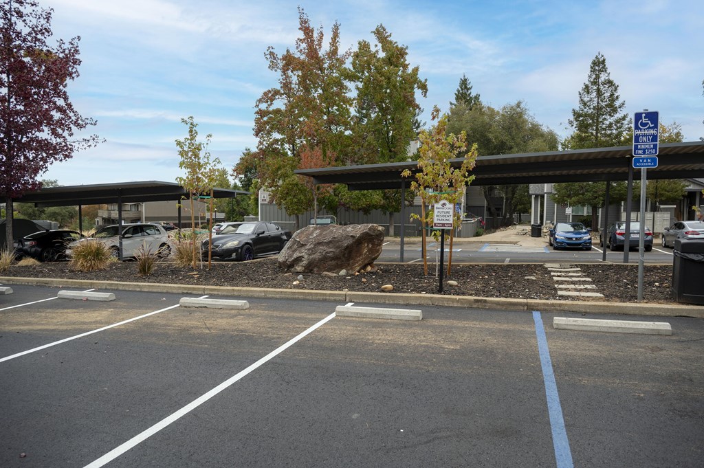 A parking lot with a blue sign on the right side at Sierra Oaks Living Apartments, Cameron Park, CA 95682