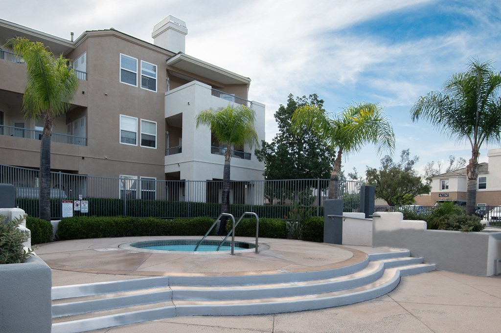 A swimming pool in front of a two-story apartment building.
