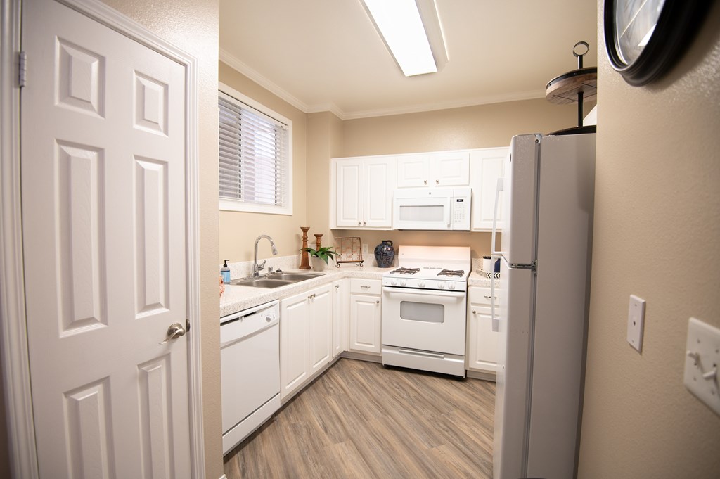 A white kitchen with a refrigerator on the right.