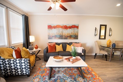 A living room with a couch, a chair, a coffee table, and a painting on the wall.