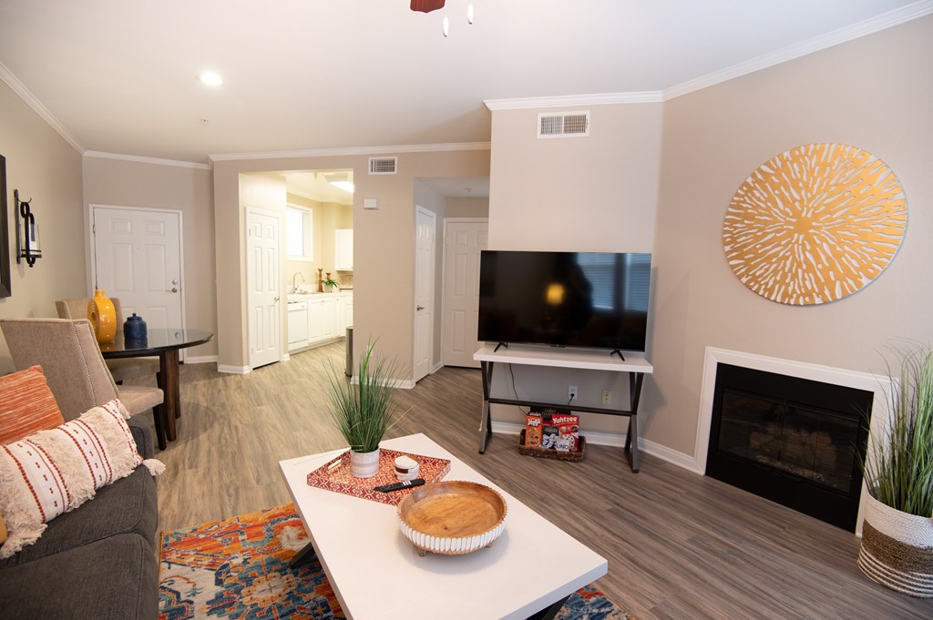 A living room with a grey couch, a white coffee table, a television, and a fireplace.