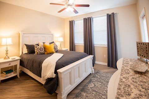 A bedroom with a large bed and a ceiling fan.