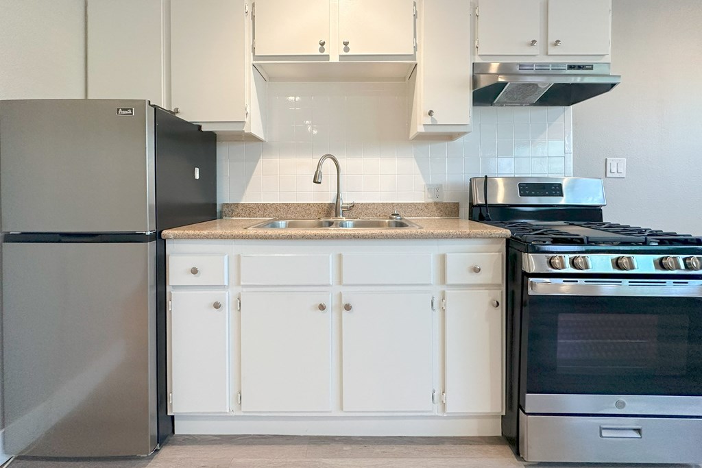 A kitchen with a black refrigerator and white cabinets.