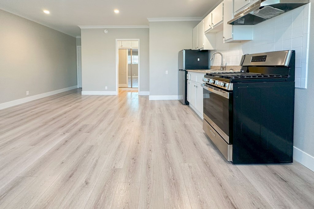 A kitchen with a black oven and wooden flooring.