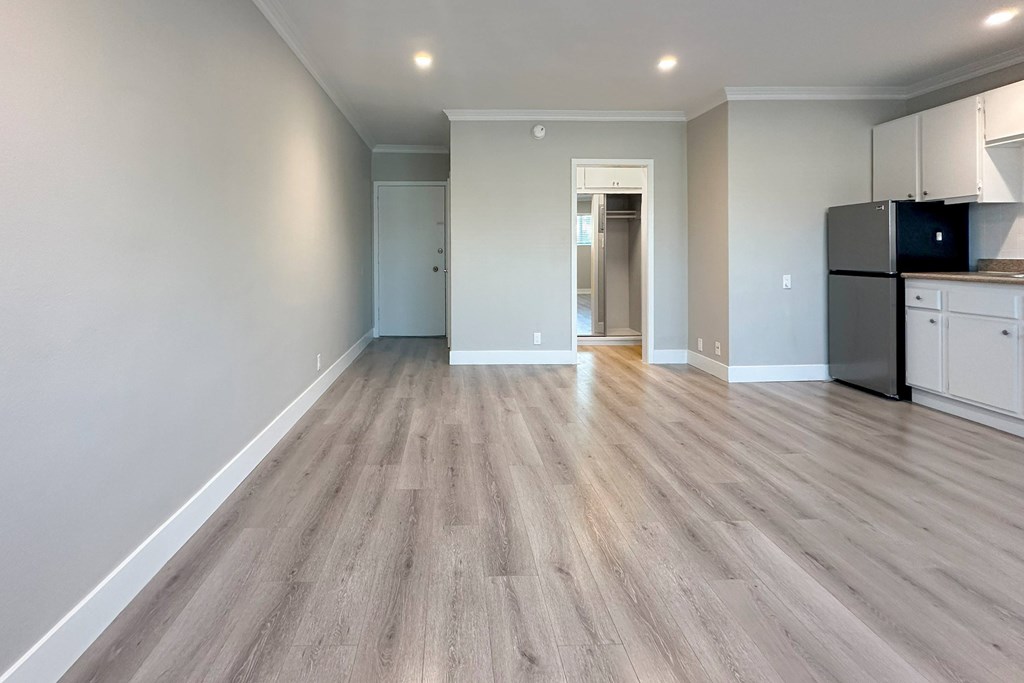 A kitchen area with a refrigerator, cabinets, and a countertop.