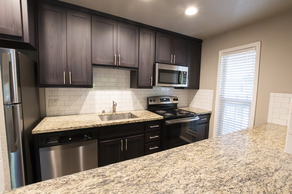 A kitchen with granite countertops and black cabinets.