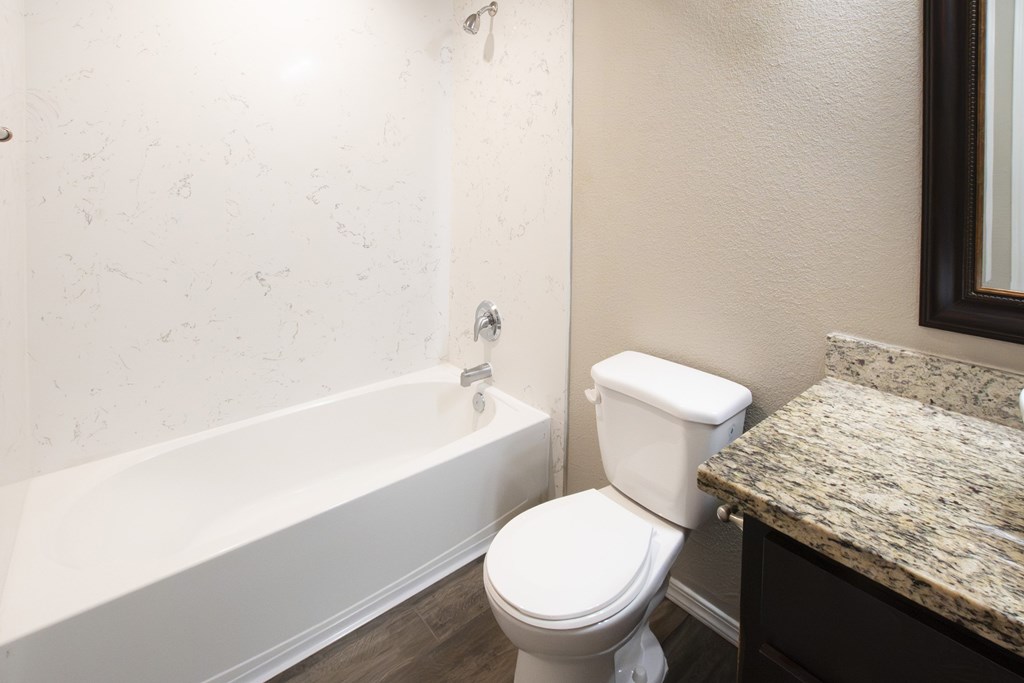 A white toilet sits next to a bathtub in a bathroom.