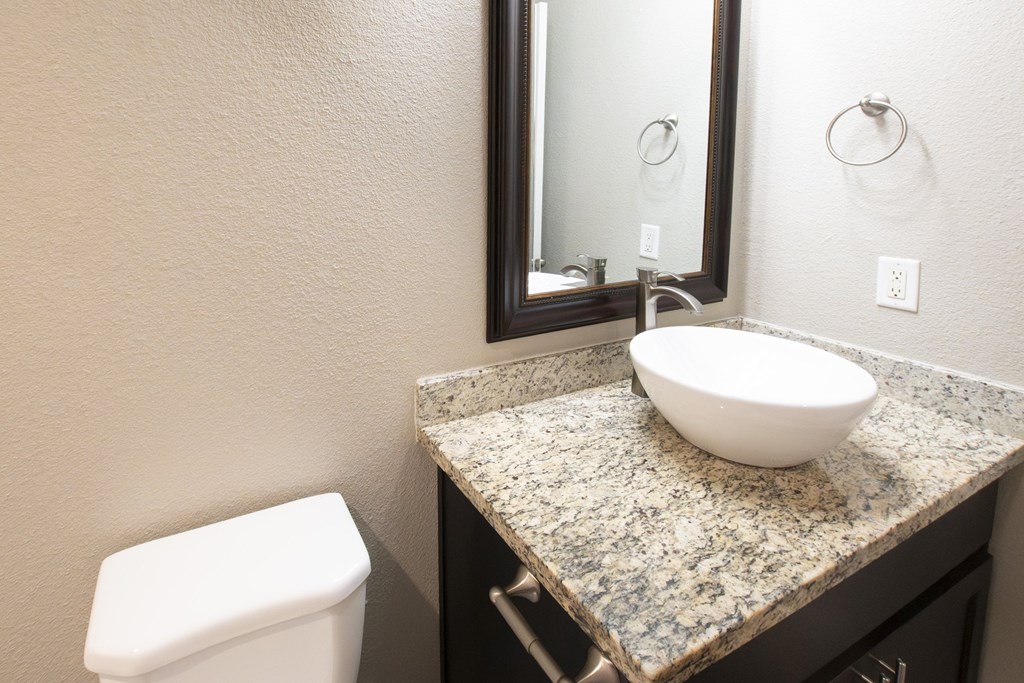 A bathroom with a granite countertop and a white toilet.