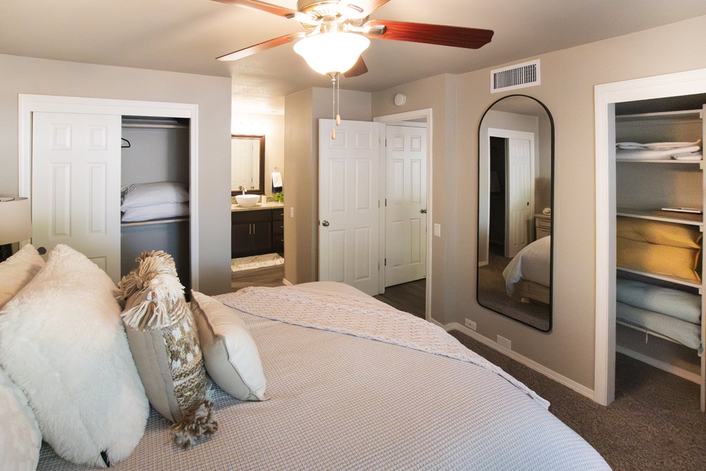 A bedroom with a bed, a ceiling fan, and a mirrored closet.
