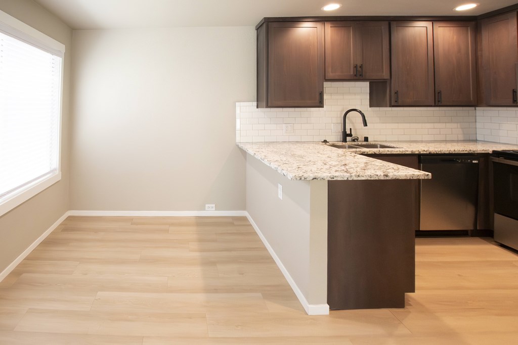 A kitchen with a white countertop and wooden cabinets.