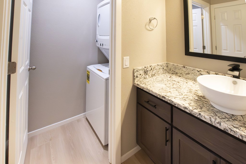 A bathroom with a sink, mirror, and a refrigerator.