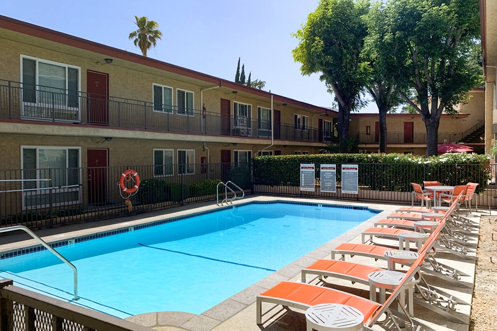 A pool with chairs around it in front of a building.