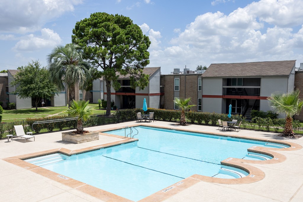 A swimming pool surrounded by palm trees and a building.