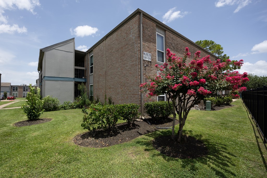 A brick building with a tree with pink flowers in front of it.