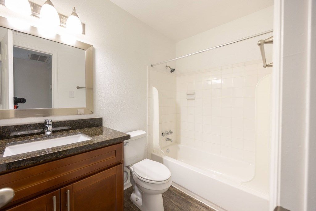 A white toilet sits in a bathroom next to a sink and a bathtub.