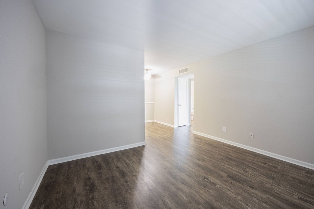 A room with wooden floors and a doorway leading to another room.