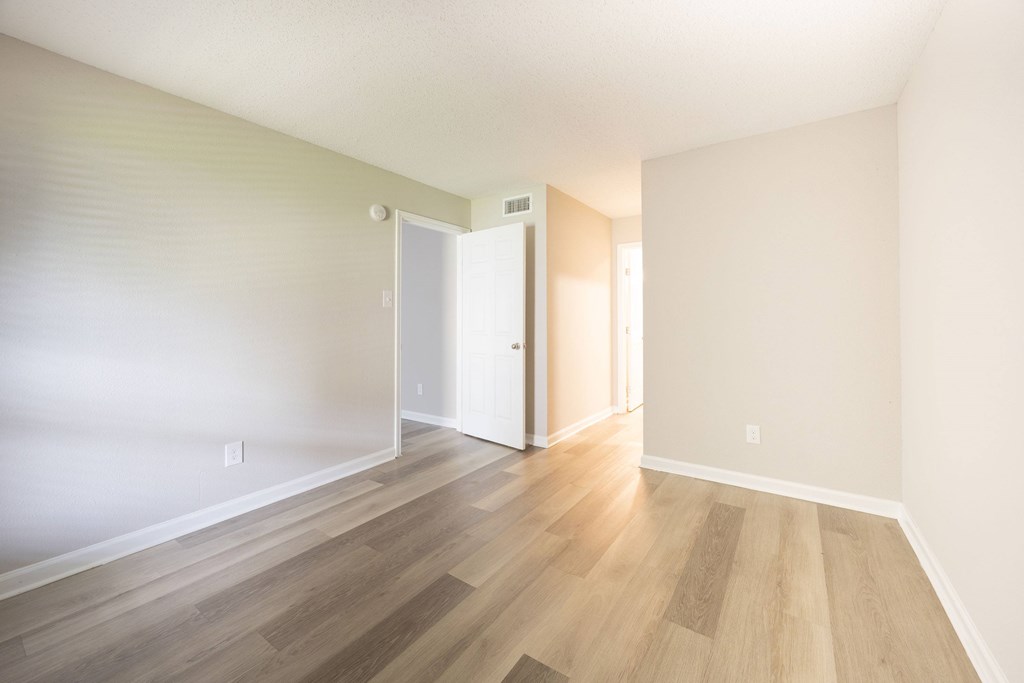 A room with a white door and wooden flooring.