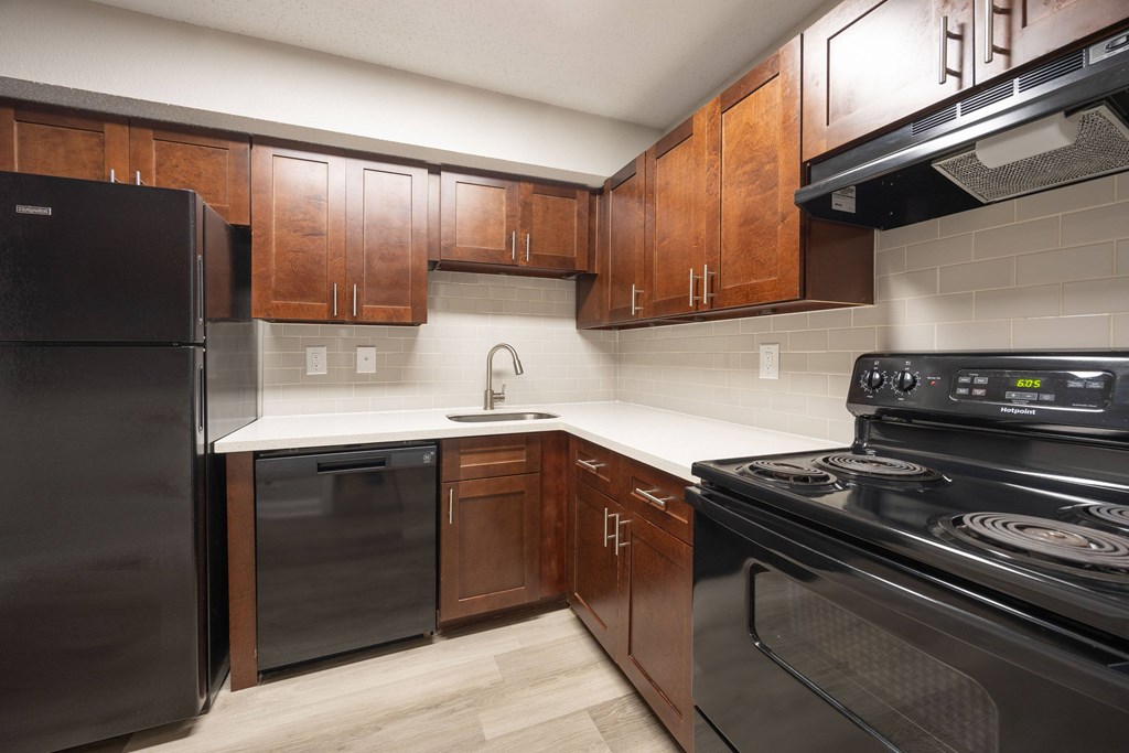A kitchen with black appliances and wooden cabinets.