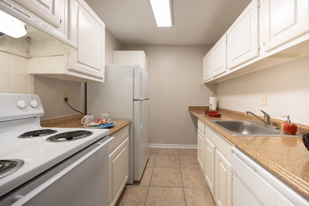 A kitchen with white cabinets and a white stove top oven.
